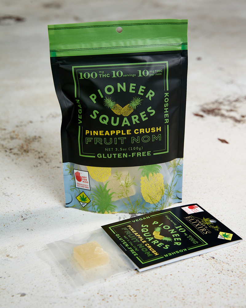 A 10-pack of Pineapple Crush Pioneer Squares sitting on a granite surface. A single serving sits in the foreground.