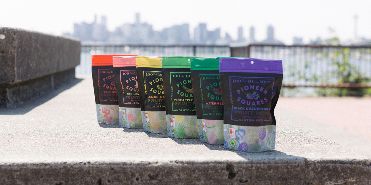 All flavors of Pioneer Squares edibles in a row, with the Seattle skyline in the background.