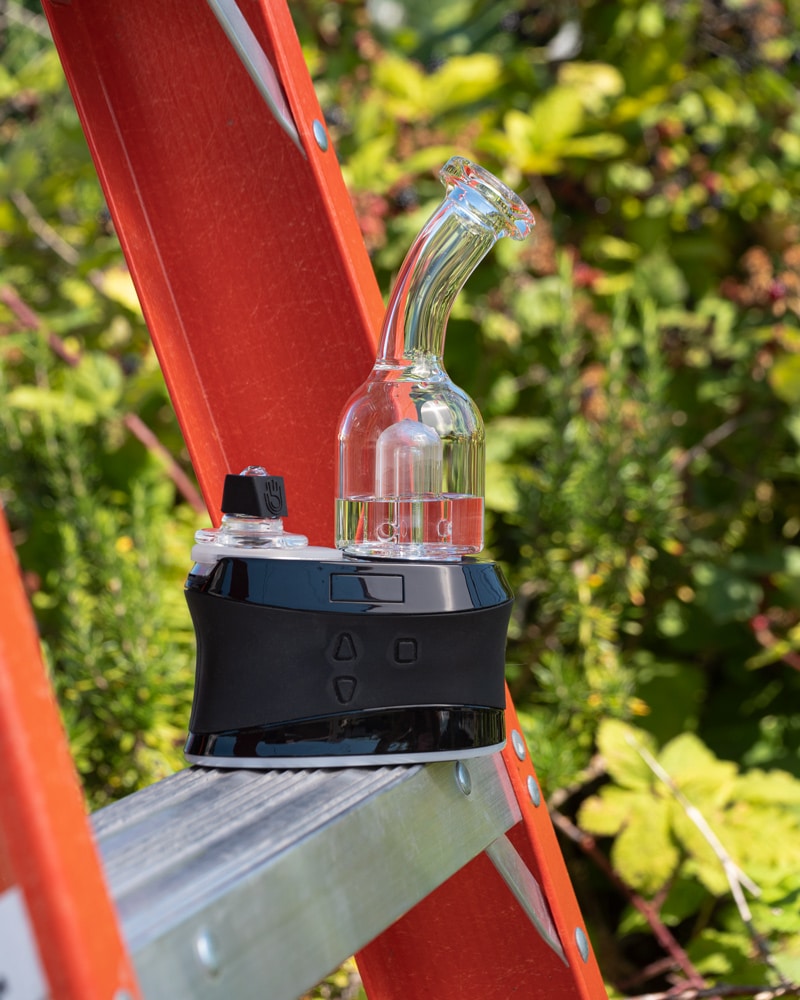 A High Five Duo e-rig sits on the rung of a ladder, with plants in the background.