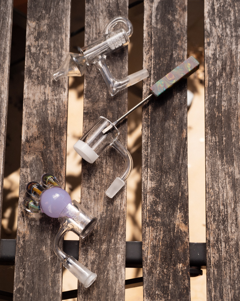 A carb cap, dab tool, and several bangers laid out on an outdoor table.